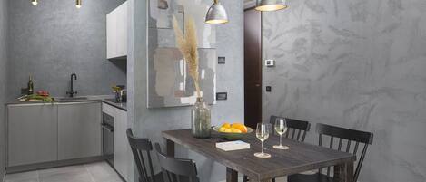 A modern kitchen with a dining area. It includes a kitchen island with a sink, a dining table with chairs, and pendant lights above the table.