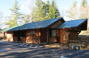 Eine Holzhütte mit grüner Dachdeckung, ein Schild, das sie als Spruce Hollow Activity Center kennzeichnet, und ein Parkplatz mit markierten Stellplätzen.