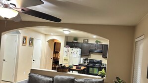 A living room with a gray sofa, a coffee table, and a ceiling fan. - Cozi 3 bedroom with pool table and full bar (Maricopa)