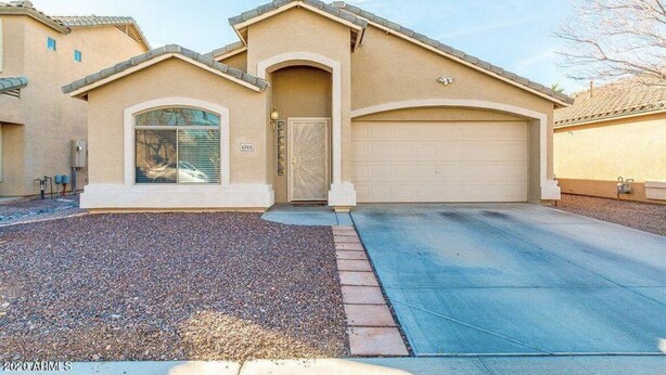 A single-story house with a beige facade, a garage, and a gravel driveway. - Cozi 3 bedroom with pool table and full bar (Maricopa)