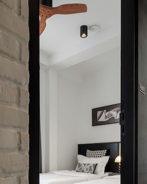 Un dormitorio con cama, cabecera, un cuadro en la pared y una lámpara de techo.