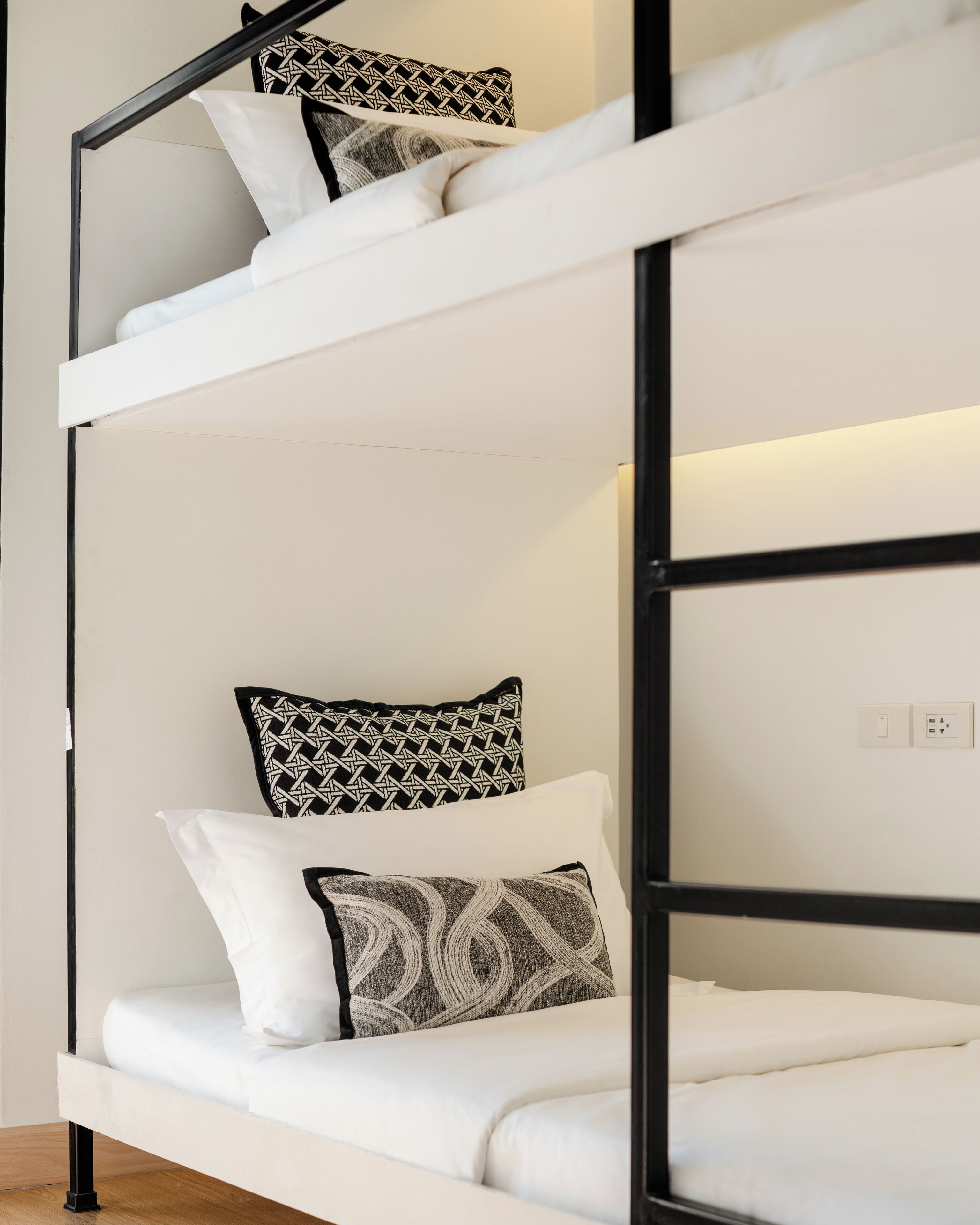 A bunk bed with white bedding and patterned pillows.
