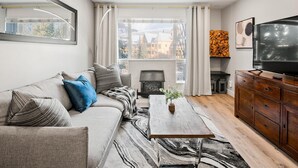 Una sala moderna con sofá, mesa de centro, televisor y chimenea.