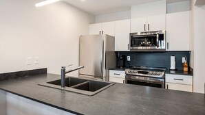 Una cocina moderna con refrigerador de acero inoxidable, horno doble y microondas.