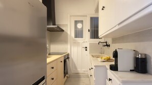 A compact kitchen with a refrigerator, oven, and sink. - Meliti Apartment in Plaka (Athens)