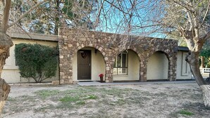 Une maison en pierre avec un porche à l’avant, une guirlande sur la porte et une plante en pot.