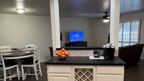 Une cuisine moderne dotée d’un îlot central, de meubles blancs, d’un plan de travail noir et d’un ventilateur de plafond.
