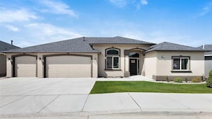 A two-story house with a garage, a front porch, and a well-maintained lawn. - Comfort by Southridge (Kennewick)