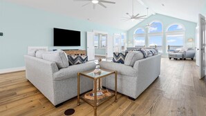 A spacious living room with a high ceiling, large windows, and a modern design. - Surfside - 2431 Bienville 4 Bedroom Home by RedAwning (Dauphin Island)
