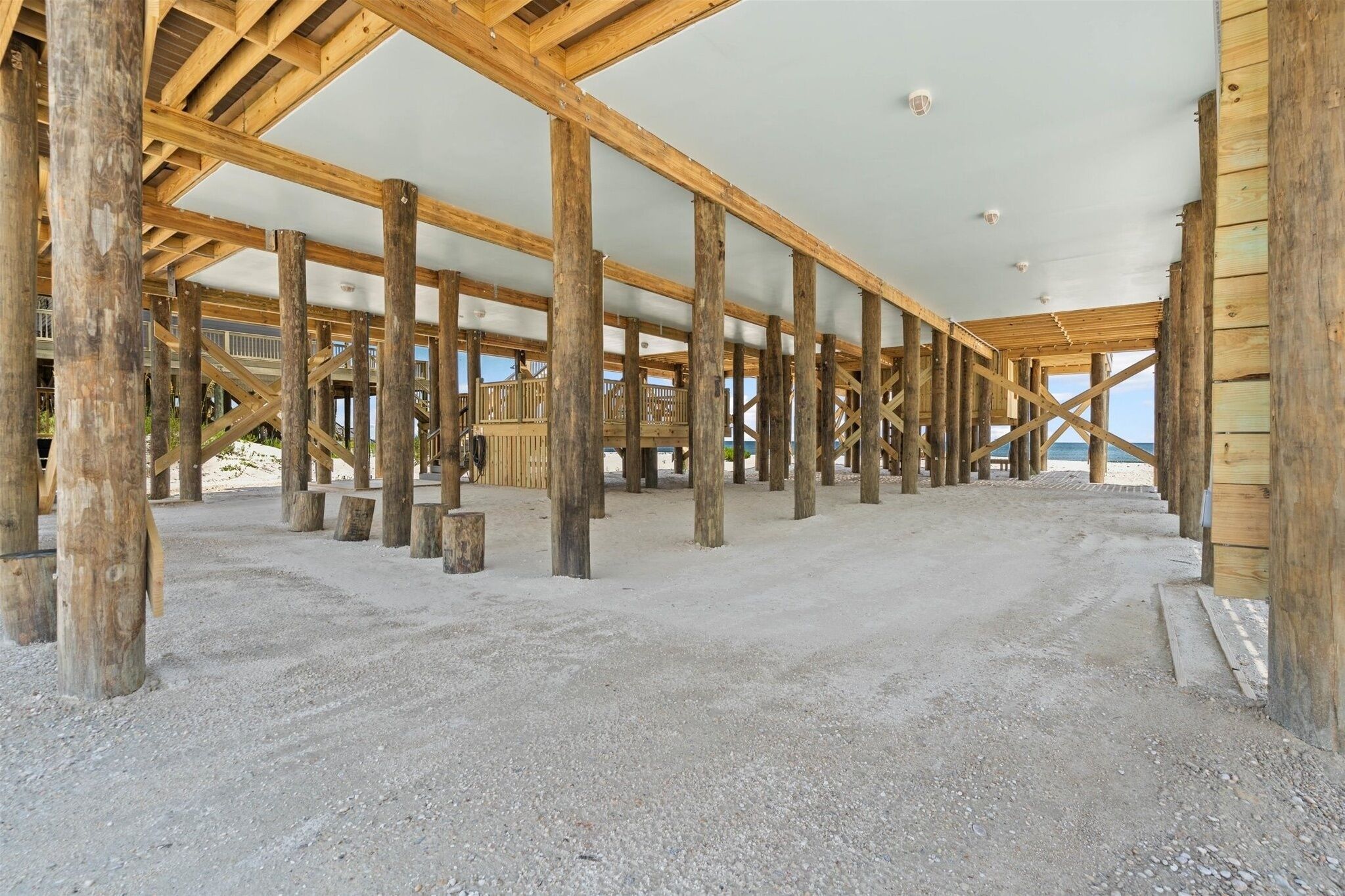 Un bâtiment en construction, avec des poutres en bois apparentes et un sol recouvert de gravier.