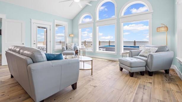 A spacious living room with a high ceiling, large windows, and a view of the outdoors. - Surfside - 2431 Bienville 4 Bedroom Home by RedAwning (Dauphin Island)