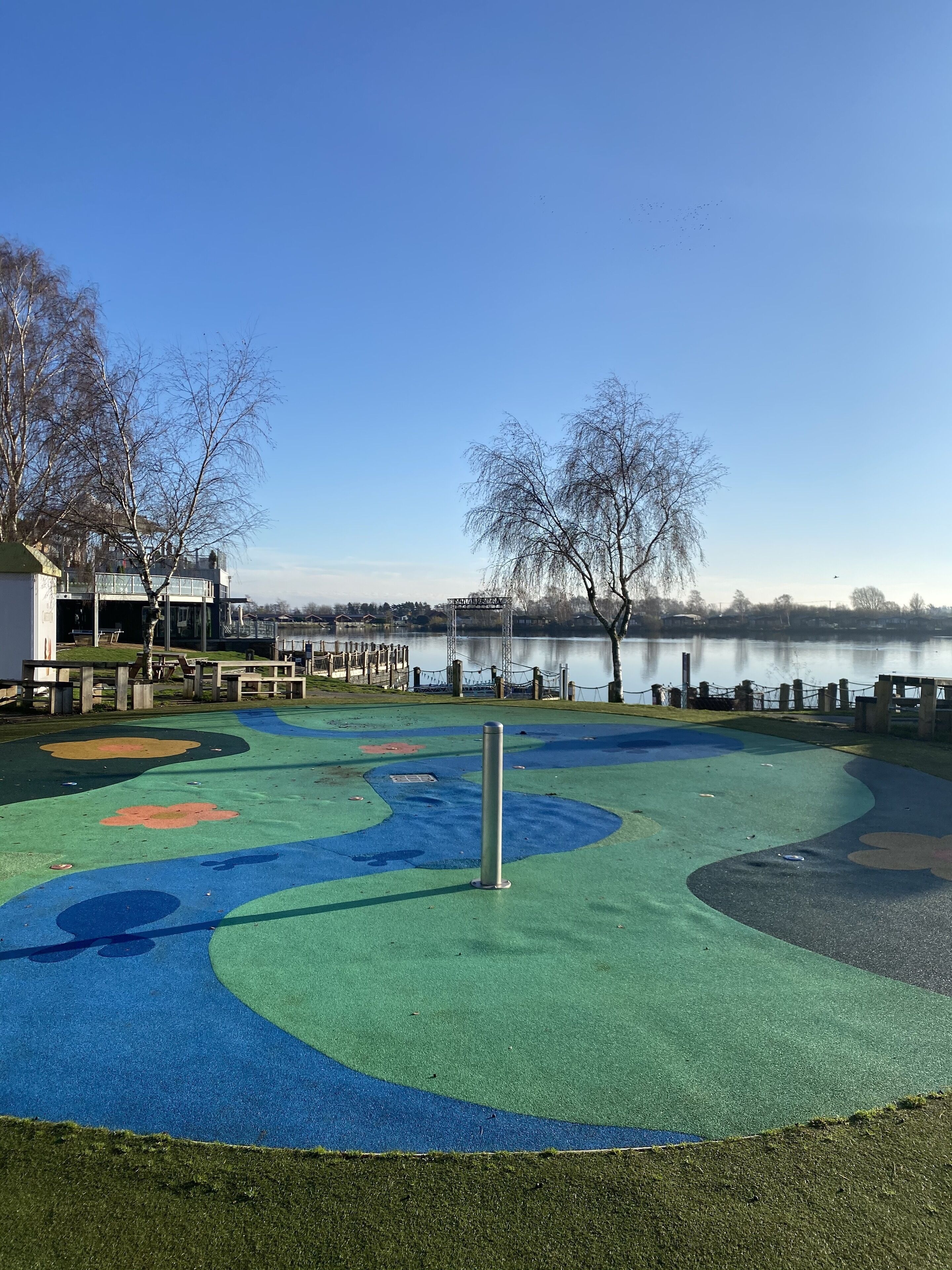 Un terrain de jeux avec des aires de jeux colorées et une vue sur un lac.