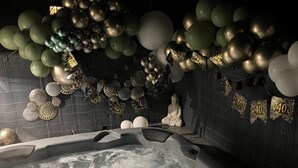 Ein Whirlpool mit dekorativen Ballons und Wandgestaltungen, darunter eine Buddha-Statue.