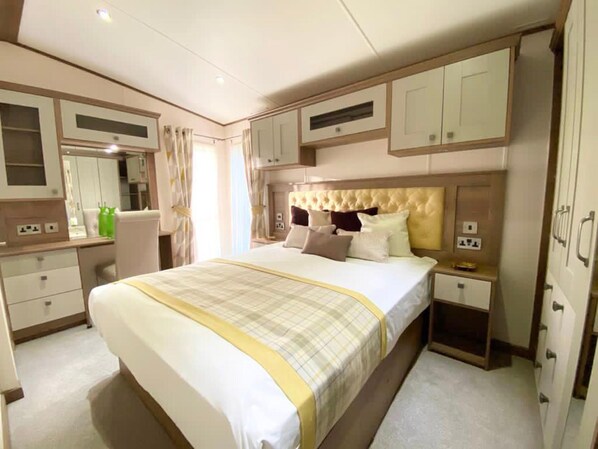 A hotel room with a large bed, a bedside table, a wardrobe, and a mirror. - Pet-friendly 3-bed Lodge for 8, Tattershall Lakes (Lincoln)