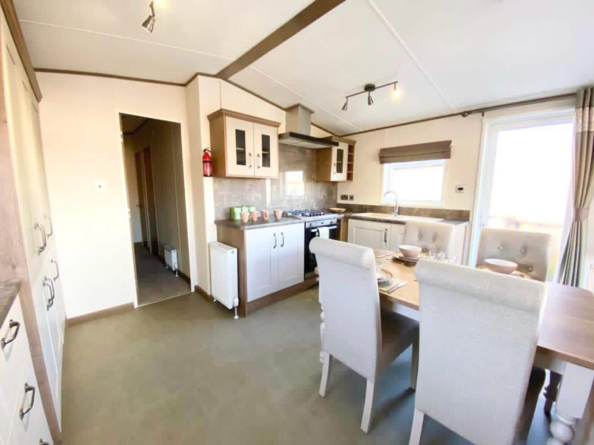 A compact kitchen with white cabinets, a stove, and a dining area with a table and chairs.