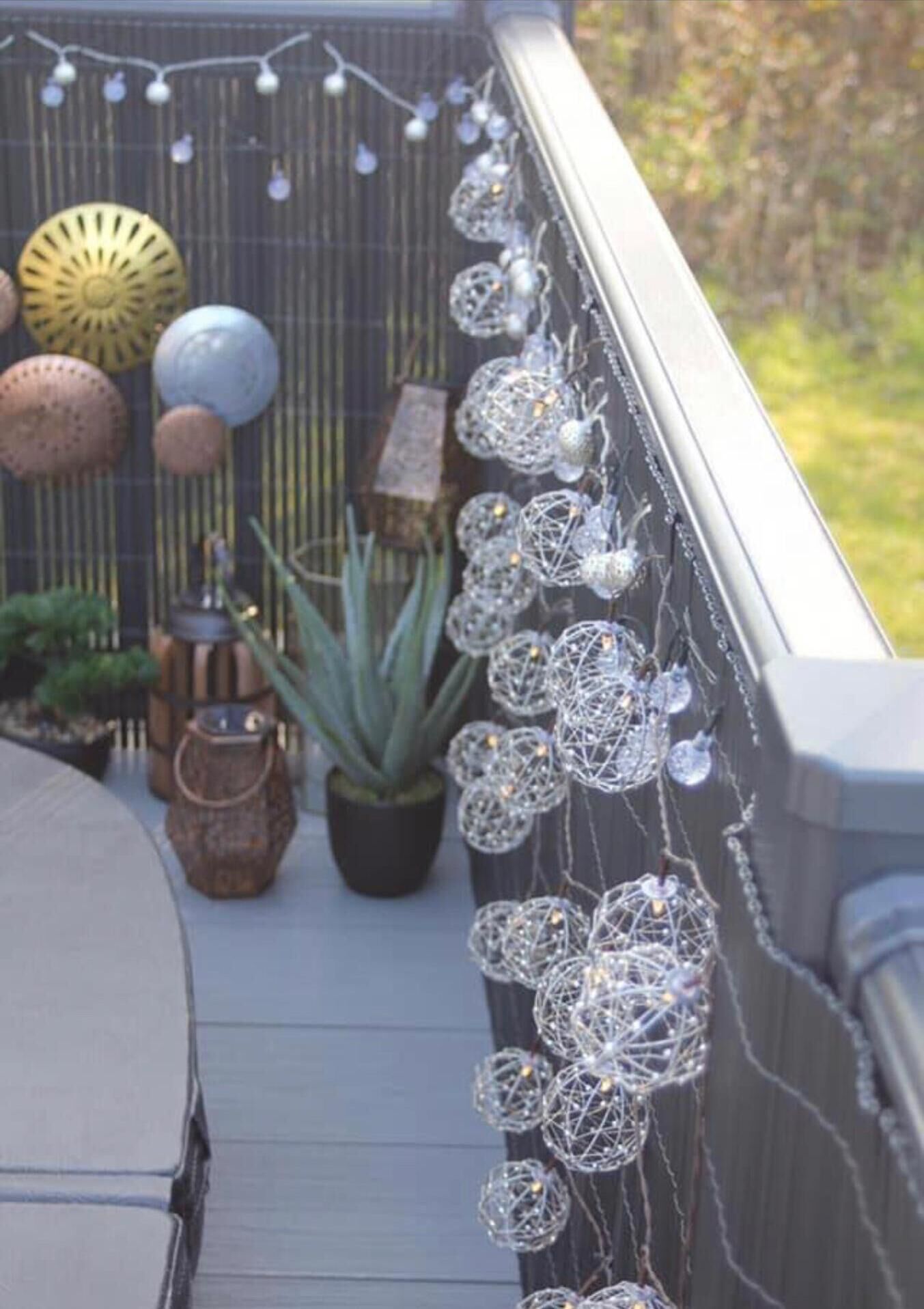 Een balkon met decoratieve verlichting, plantenbakken en diverse decoraties.