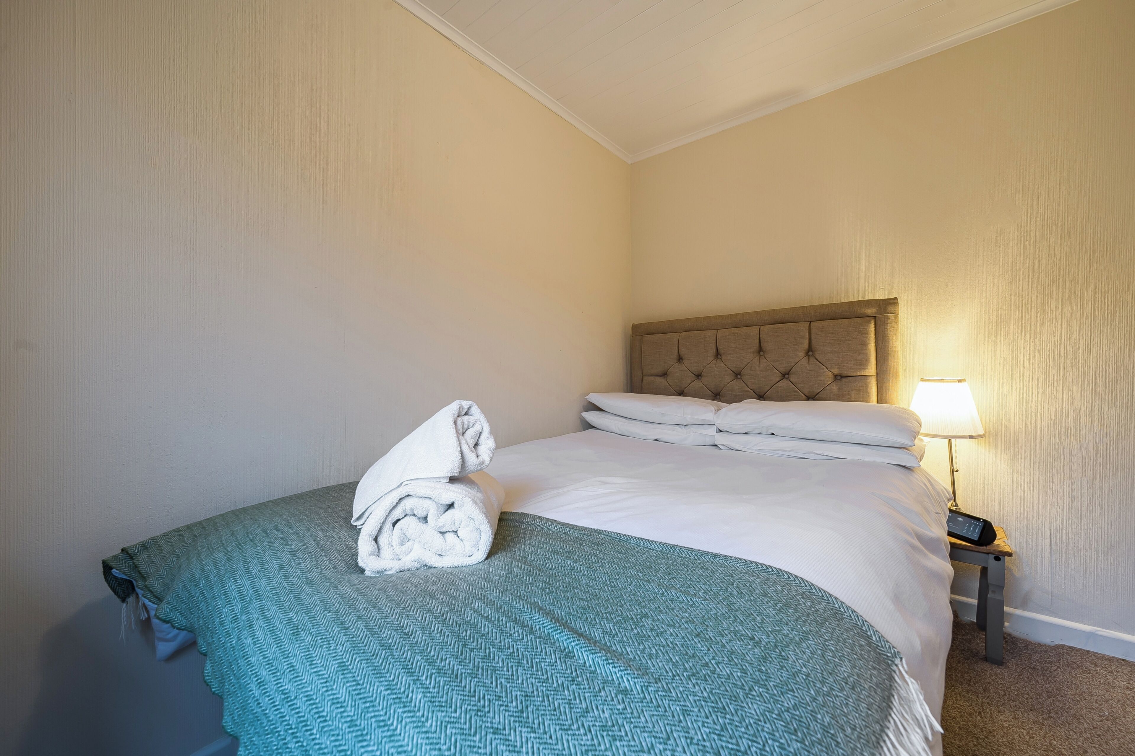 Une chambre d’hôtel avec un lit, une table de chevet et une lampe.