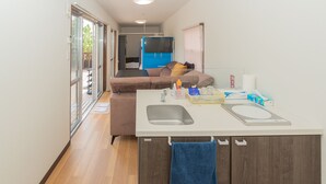 Une petite cuisine équipée comprenant un évier, un petit plan de travail et une serviette bleue accrochée à l’armoire.
