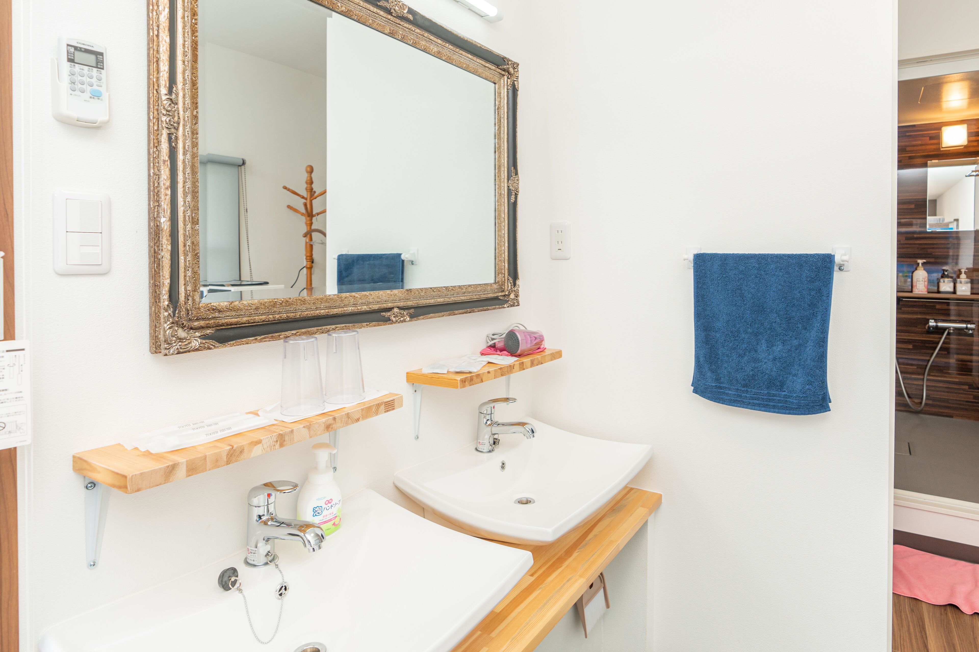 A bathroom with two sinks, a large mirror, and a blue towel on the wall.