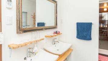 A bathroom with two sinks, a large mirror, and a blue towel on the wall.