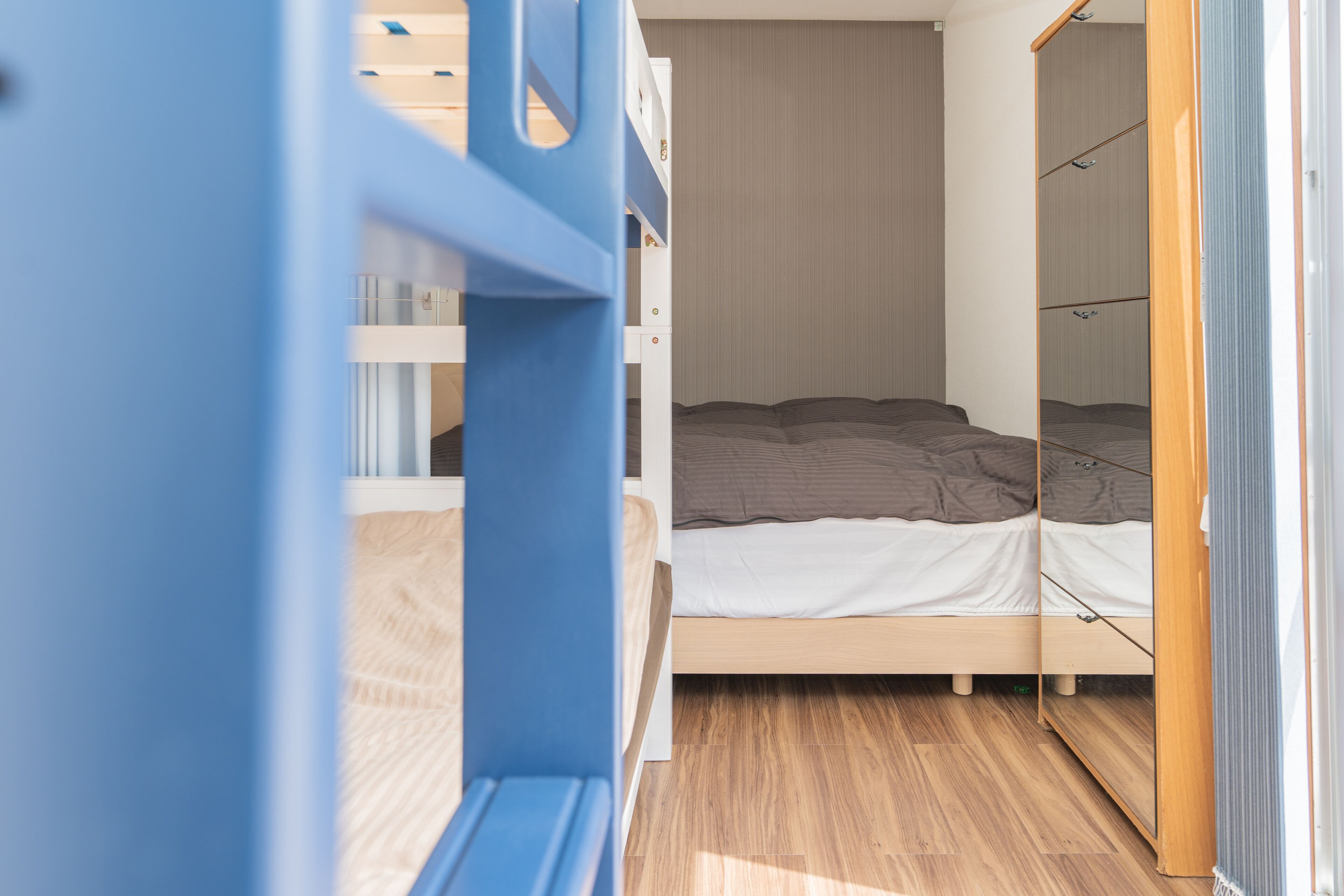 Une chambre avec un lit superposé, une armoire et un miroir.