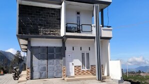 Una casa de dos pisos con balcón, garaje y entrada para vehículos.