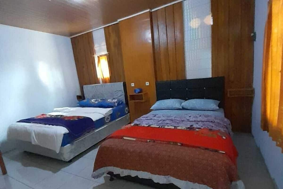 Une chambre avec deux lits, un lambris en bois et un sol carrelé.