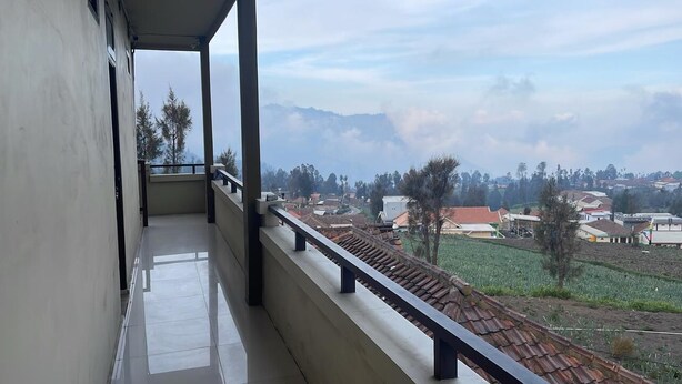 Un balcón con vista a una zona residencial y montañas a lo lejos.