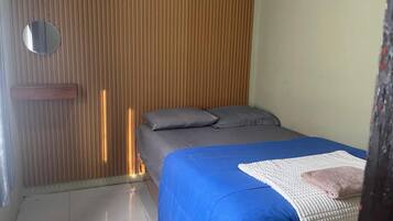 A bedroom with a bed, a bedside table, a mirror, and a wooden slat wall.