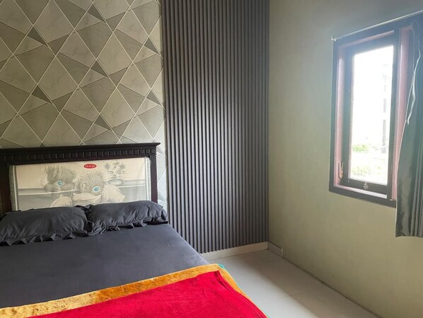 A bedroom with a bed, a window, and a wall with a geometric pattern. - Bromo Semesta Guesthouse (Ngadisari)