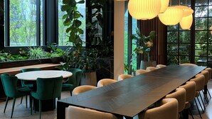 Una sala de conferencias moderna con una larga mesa y sillas, ventanas amplias y lámparas colgantes.