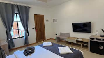 A modern hotel room with two beds, a flat-screen TV, a desk, and a small fridge.
