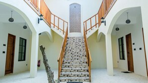 A staircase with wooden railings and tiled steps, flanked by white walls and wooden doors. - Ahiva Village (Fulhadhoo)