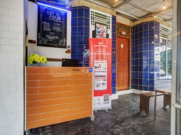 A reception area with a wooden counter, a chalkboard menu, and a QR code poster. - Hotel O Desa Wisata Sumber Agung Syariah (Bandar Lampung)