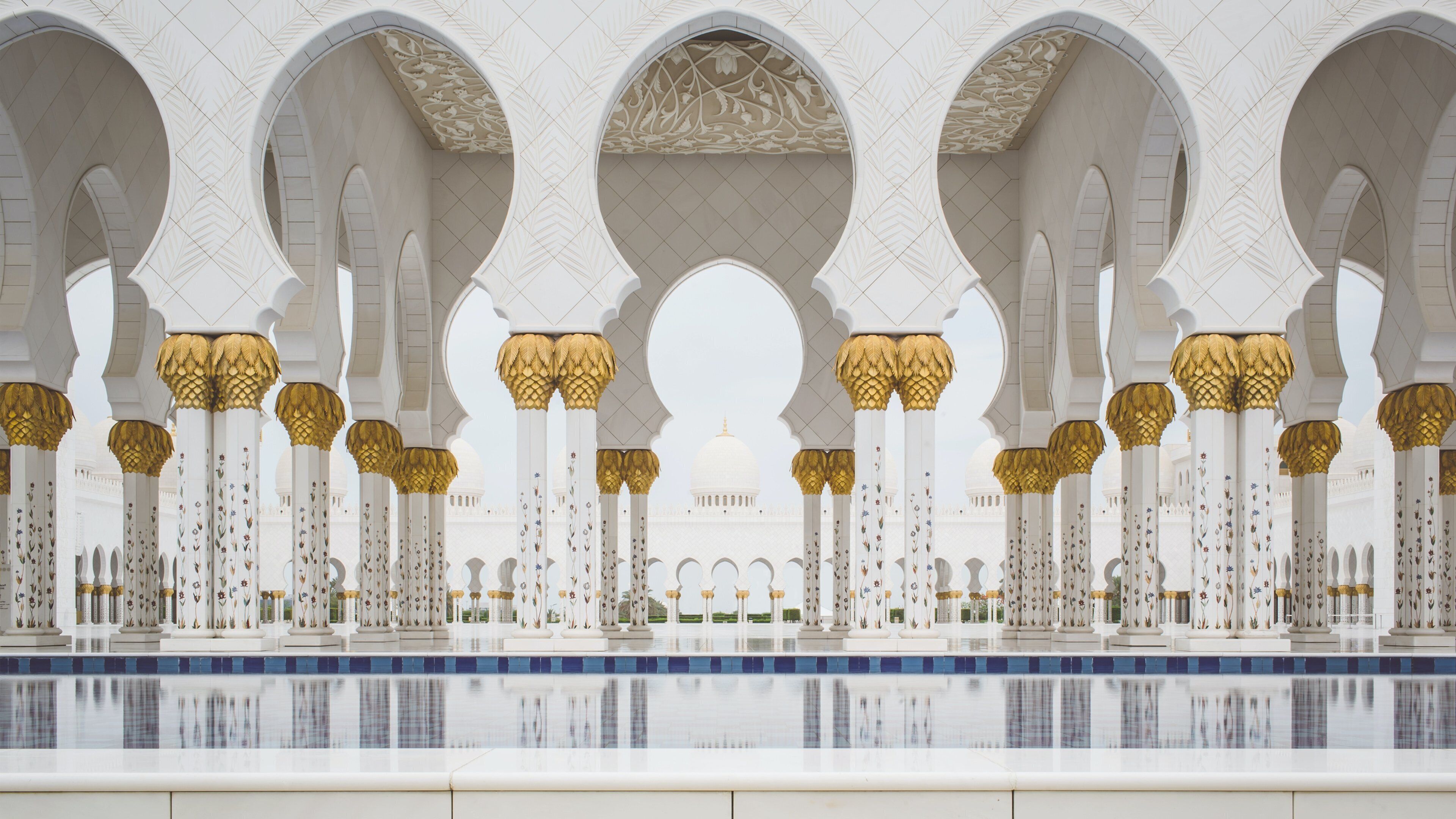 Diseño arquitectónico simétrico con columnas y arcos blancos, una cúpula central y un estanque reflectante.