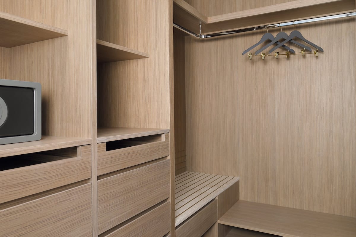 A modern, minimalist closet with wooden shelves and a built-in safe.