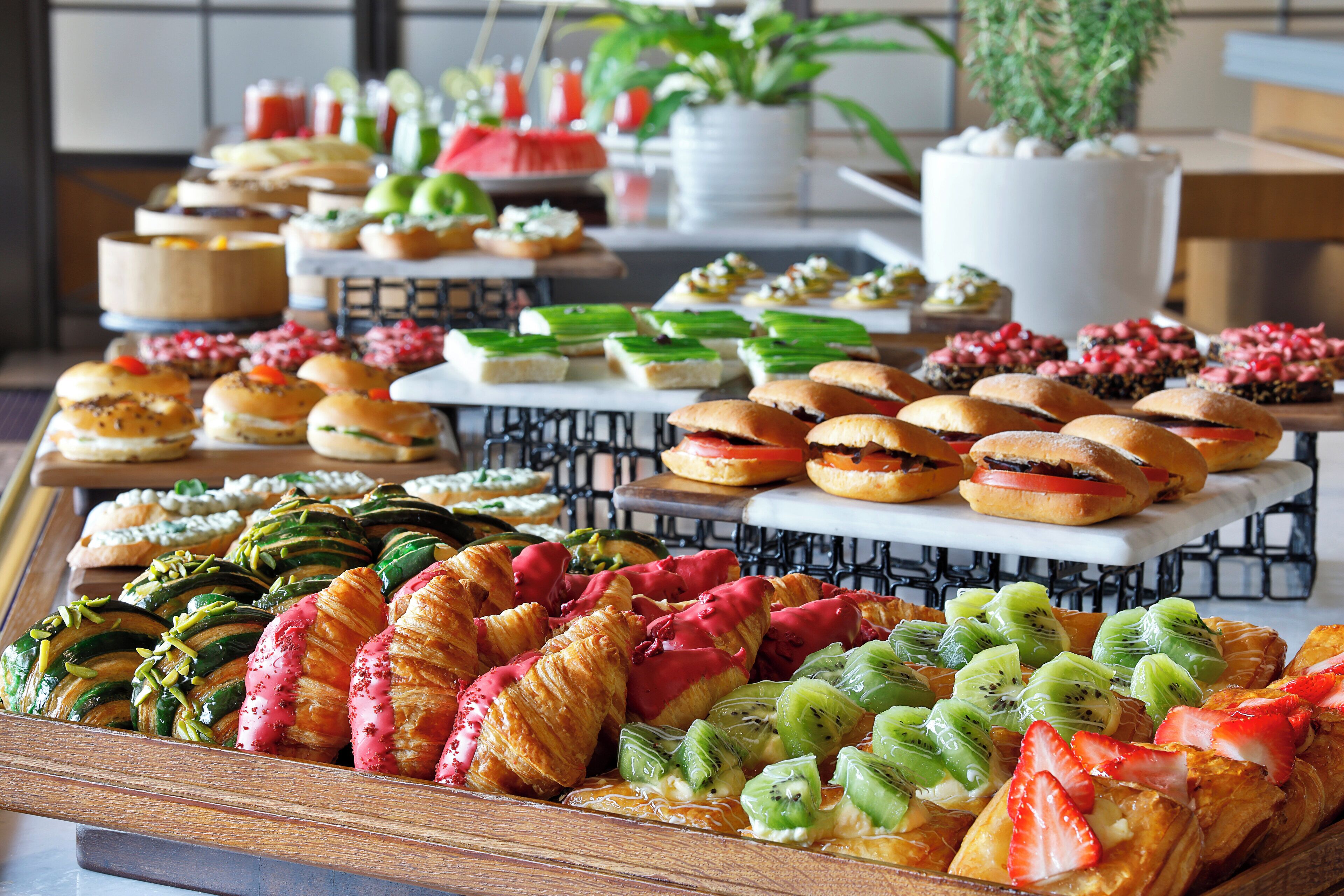 Un bufé con diferentes opciones de comida, incluyendo pasteles, sándwiches y fruta.