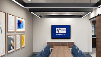Una sala de conferencias con una mesa larga, sillas azules, obras de arte enmarcadas en las paredes y un cartel de Holiday Inn Express en la pared.