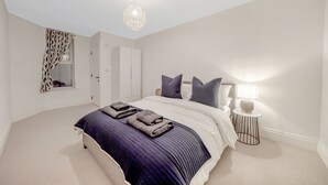 Une chambre à coucher avec un grand lit, une table de chevet avec une lampe, un miroir et une armoire.