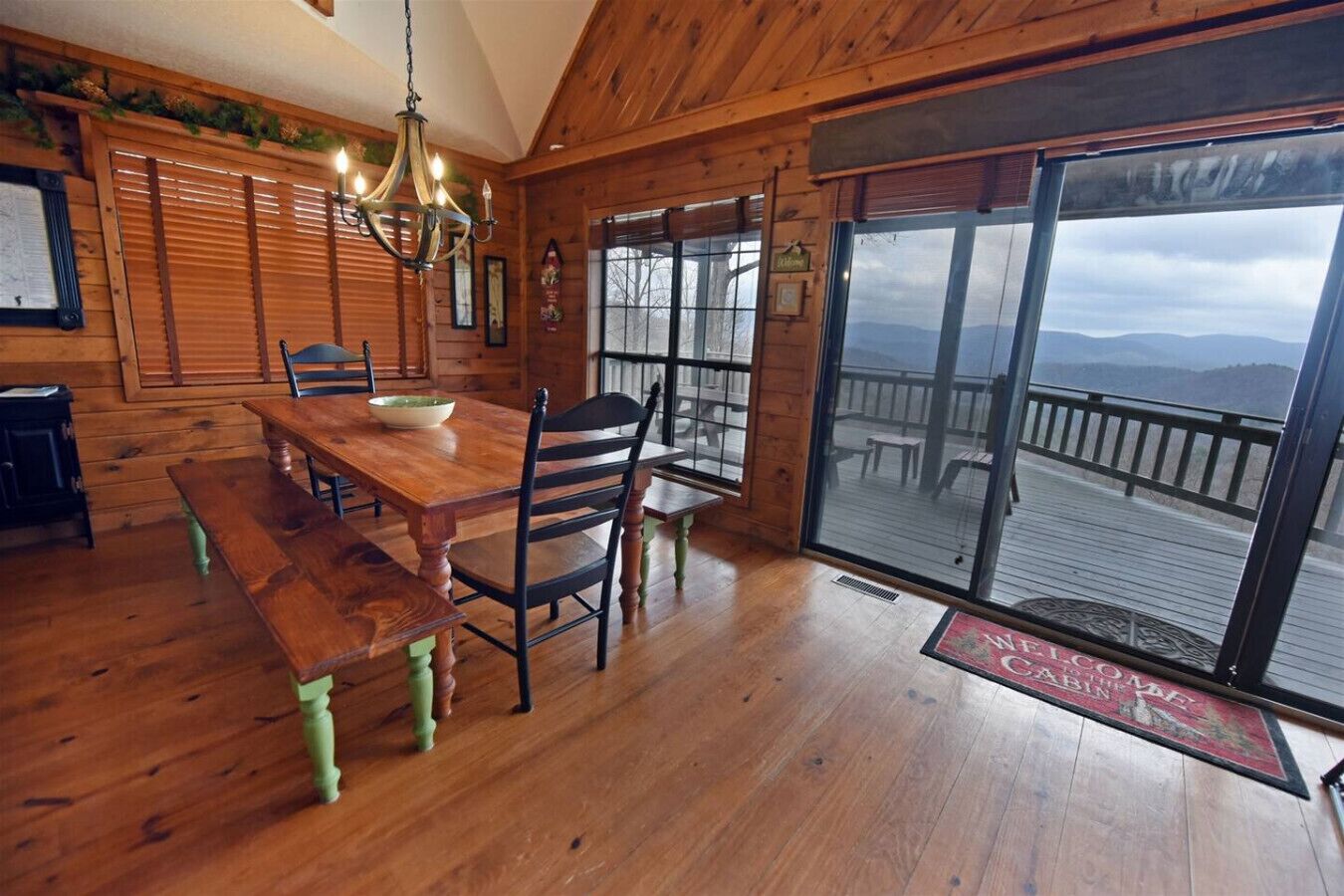 A wooden interior with a dining table, chairs, and a chandelier.