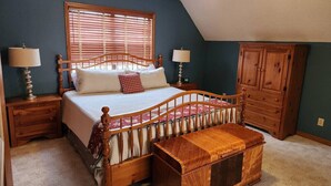 A bedroom with a wooden bed, a nightstand, a dresser, and a bench.