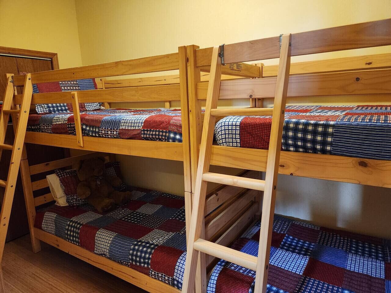 A bunk bed with a ladder, wooden headboard, and a quilted bedspread.
