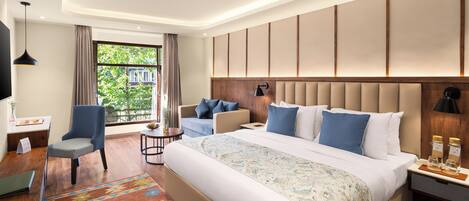 Habitación de hotel moderna con una cama grande, un escritorio, una silla y vistas a zonas verdes.