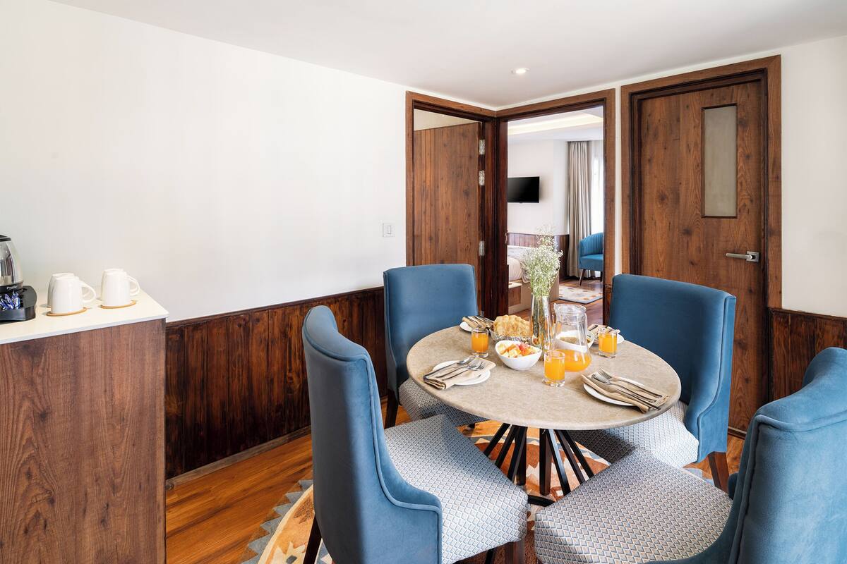 A dining area with a round table, blue upholstered chairs, and a breakfast setting.