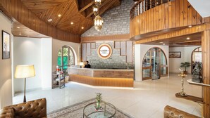 A hotel lobby with a reception desk, leather sofas, a coffee table, and a chandelier. - Kanishka, Manali- AM Hotel Kollection (Manali)