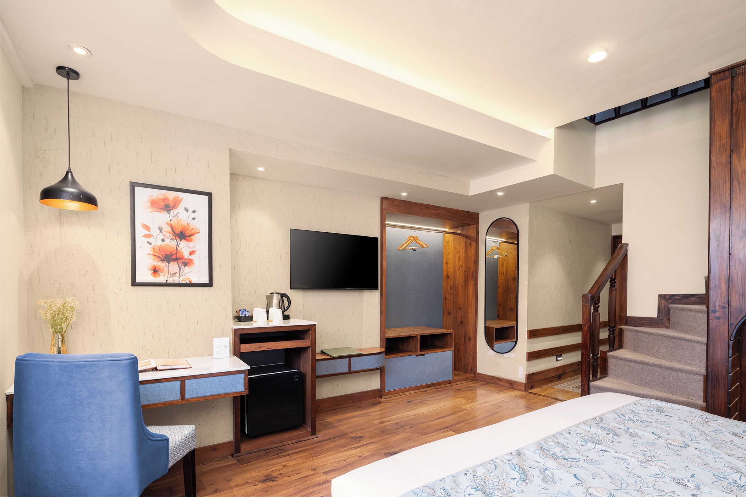 Un dormitorio moderno con cama, escritorio, silla y televisor montado en la pared.