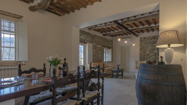 Un coin repas avec une table en bois dressée pour quatre personnes, des murs en pierre et un plafond rustique.