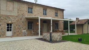 Un bâtiment en pierre doté d’un patio couvert, d’un espace extérieur aménagé pour s’asseoir et d’un jardin bien entretenu.