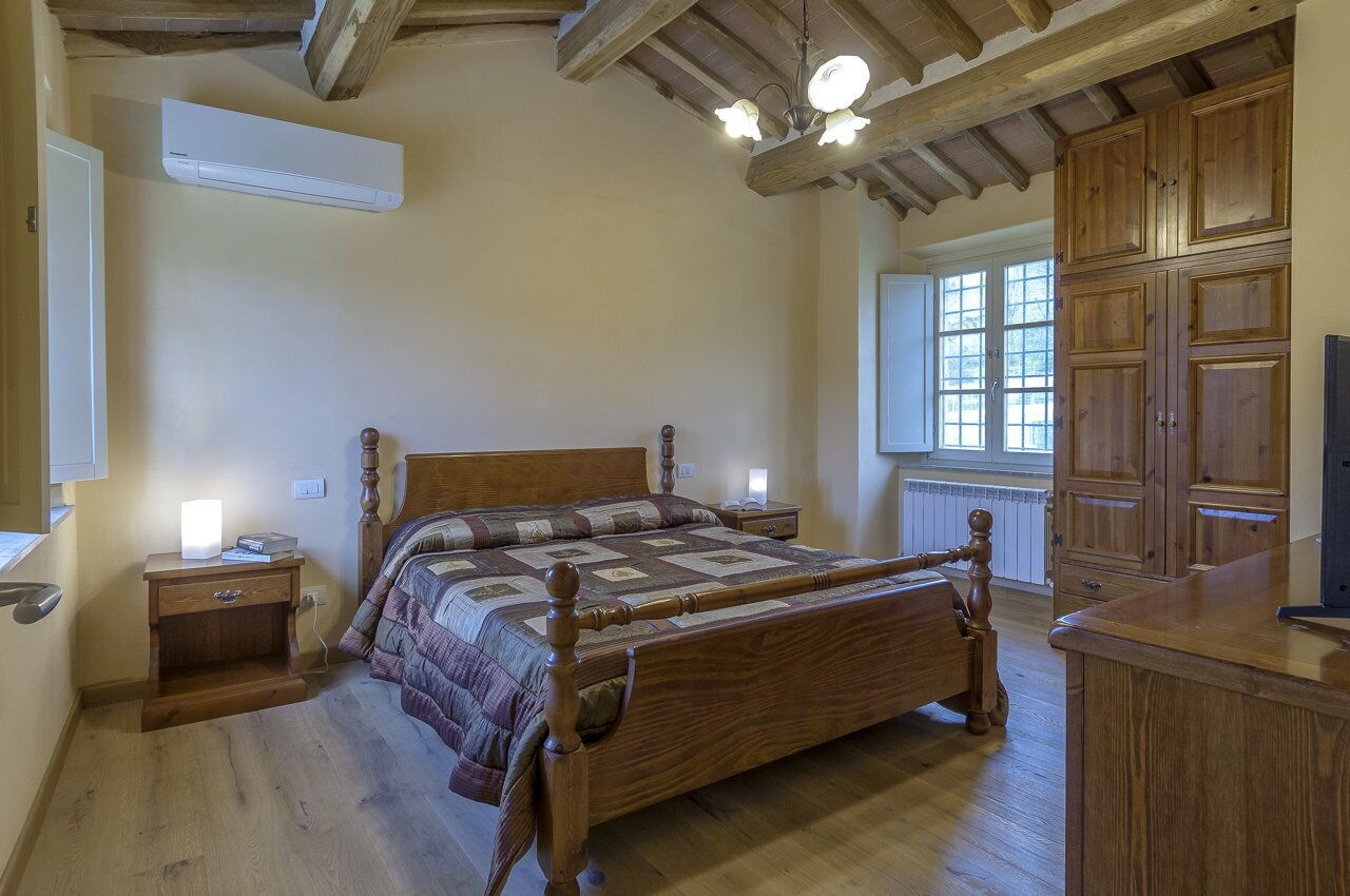 A bedroom with a wooden bed, nightstands, a wardrobe, and a window with natural light.