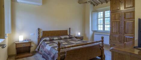 A bedroom with a wooden bed, nightstands, a wardrobe, and a window with natural light.